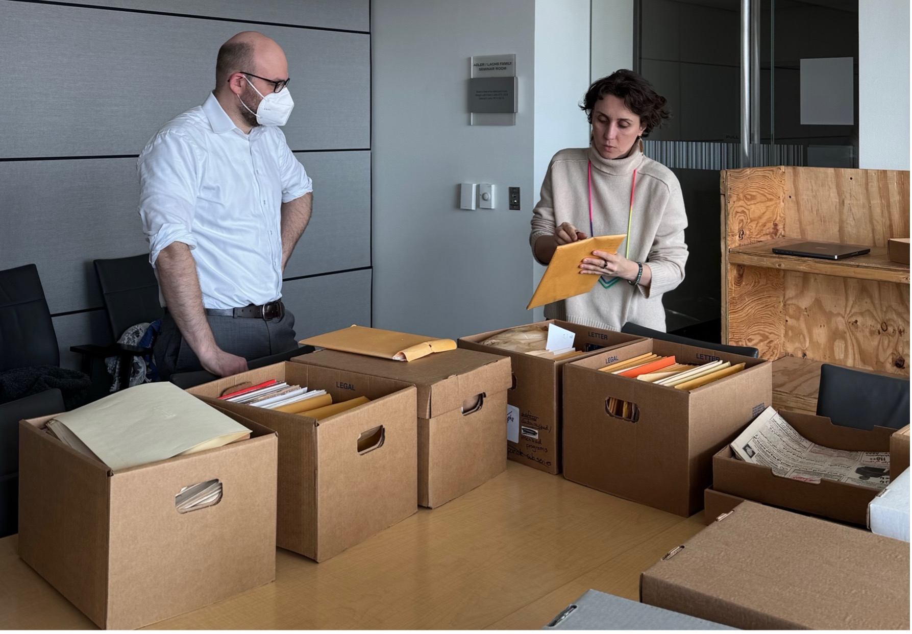 A man and a woman sift through boxes of archived documents