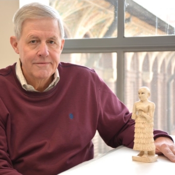 Photo Of Richard Zettler Sitting With An Ancient Statue On A Table In Front Of Him