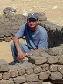 Photo Of Josef W. Wegner Kneeling Inside Ancient Brick Wall In Egypt