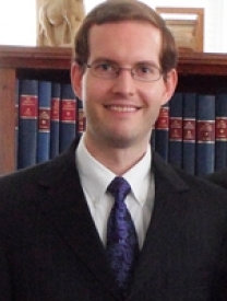 Photo Of Joshua Jeffers Standing In Front Of A Bookshelf